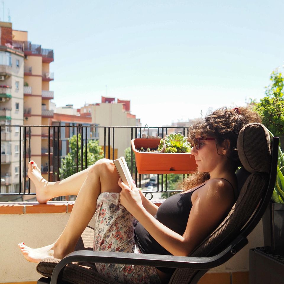Wie sich 7 Erholungstypen von Stressphasen erholen: Frau liest ein Buch auf dem Balkon
