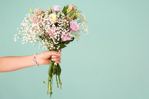 Teamtalk: Eine Frauenhand hält einen Blumenstrauß vor einem türkisen Hintergrund