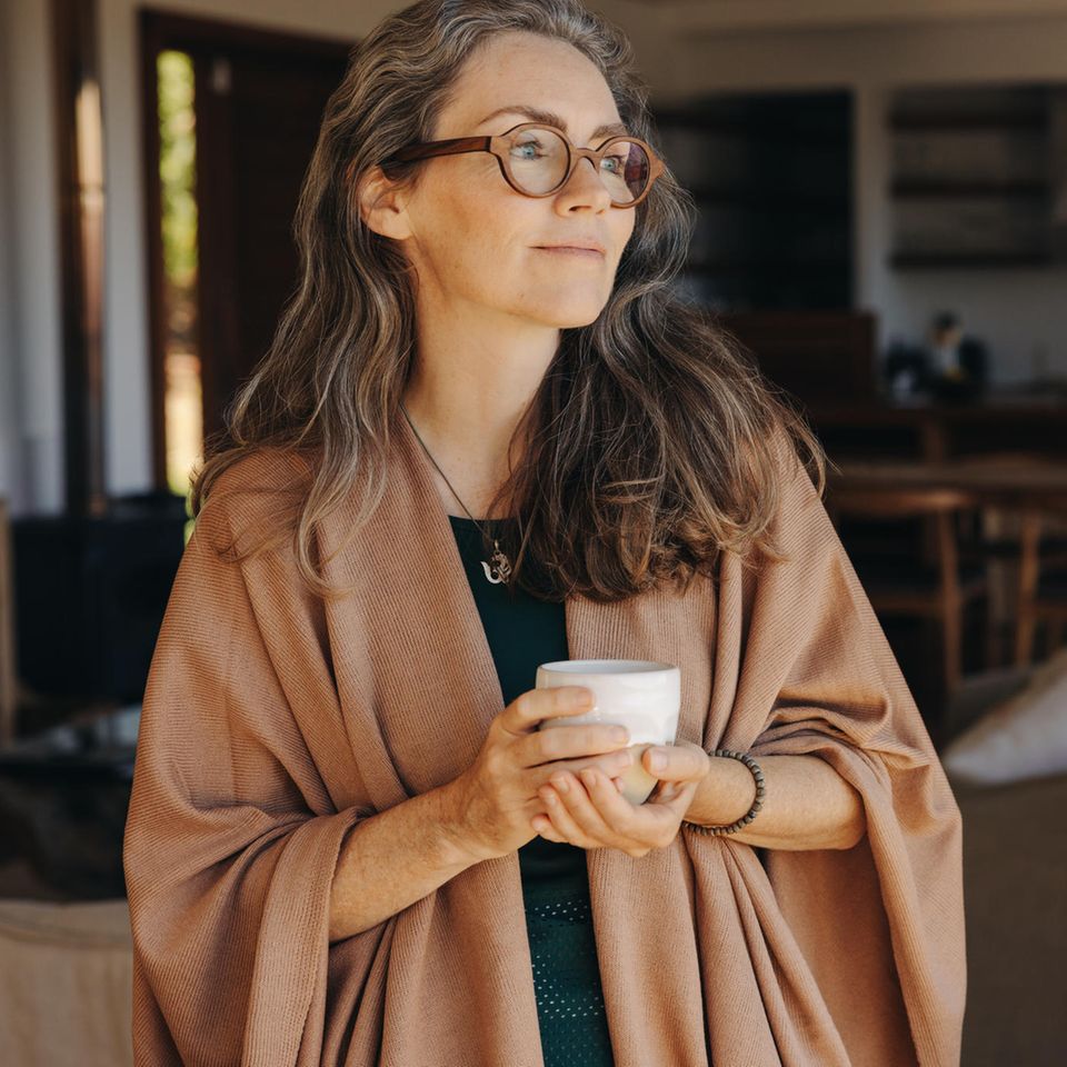 Nachdenkliche Frau mit Tee im Wohnzimmer: 4 Eigenschaften emotional reifer Menschen