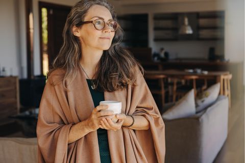 Nachdenkliche Frau mit Tee im Wohnzimmer: 4 Eigenschaften emotional reifer Menschen