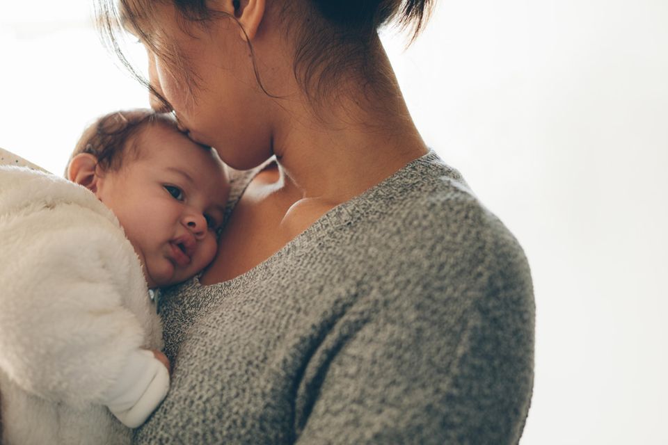 Rückbildung: Eine junge Mutter hat ein Baby auf dem Arm
