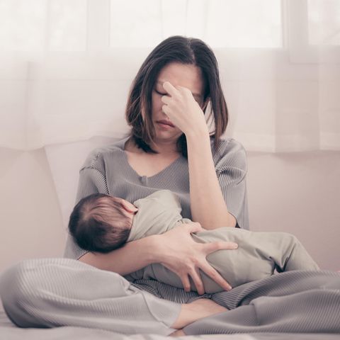 Faces of Moms: Eine erschöpfte junge Frau mit einem Säugling im Arm