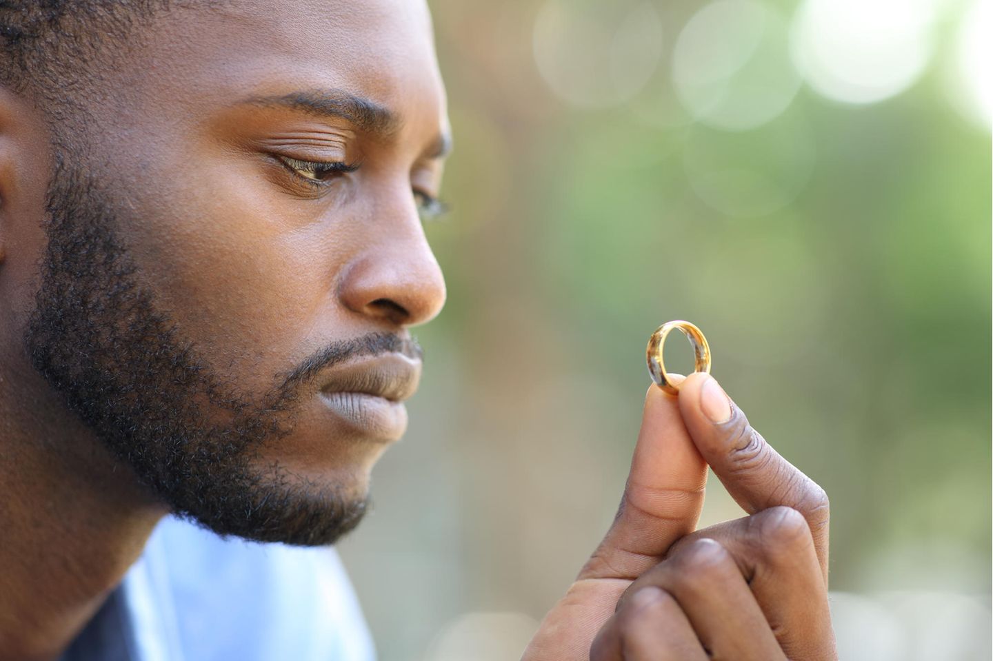 Ein Mann schaut fragend auf einen Ehering.