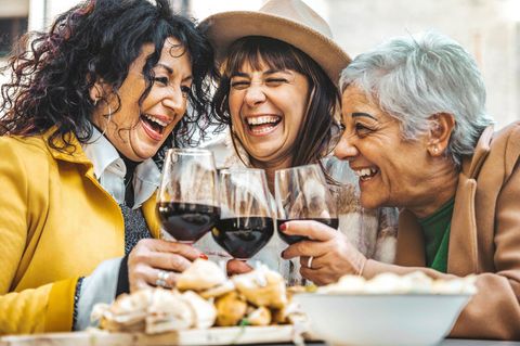 Drei Frauen stoßen mit Wein aufeinander an