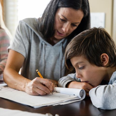 Mutter schreibt Hausaufgaben für ihren Sohn