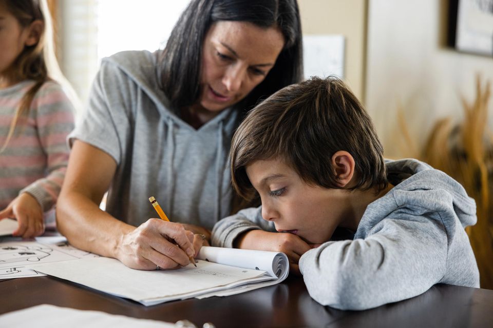 Mutter schreibt Hausaufgaben für ihren Sohn