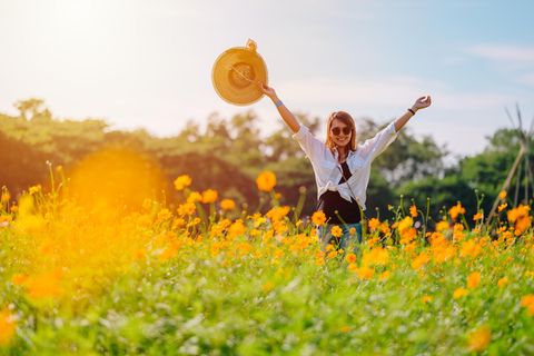 Mai-Horoskop: Eine fröhliche Frau auf einer Blumenwiese