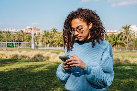 Junge Frau schaut ernst auf ihr Handy: 7 Anzeichen, dass du eine schwierige Person bist