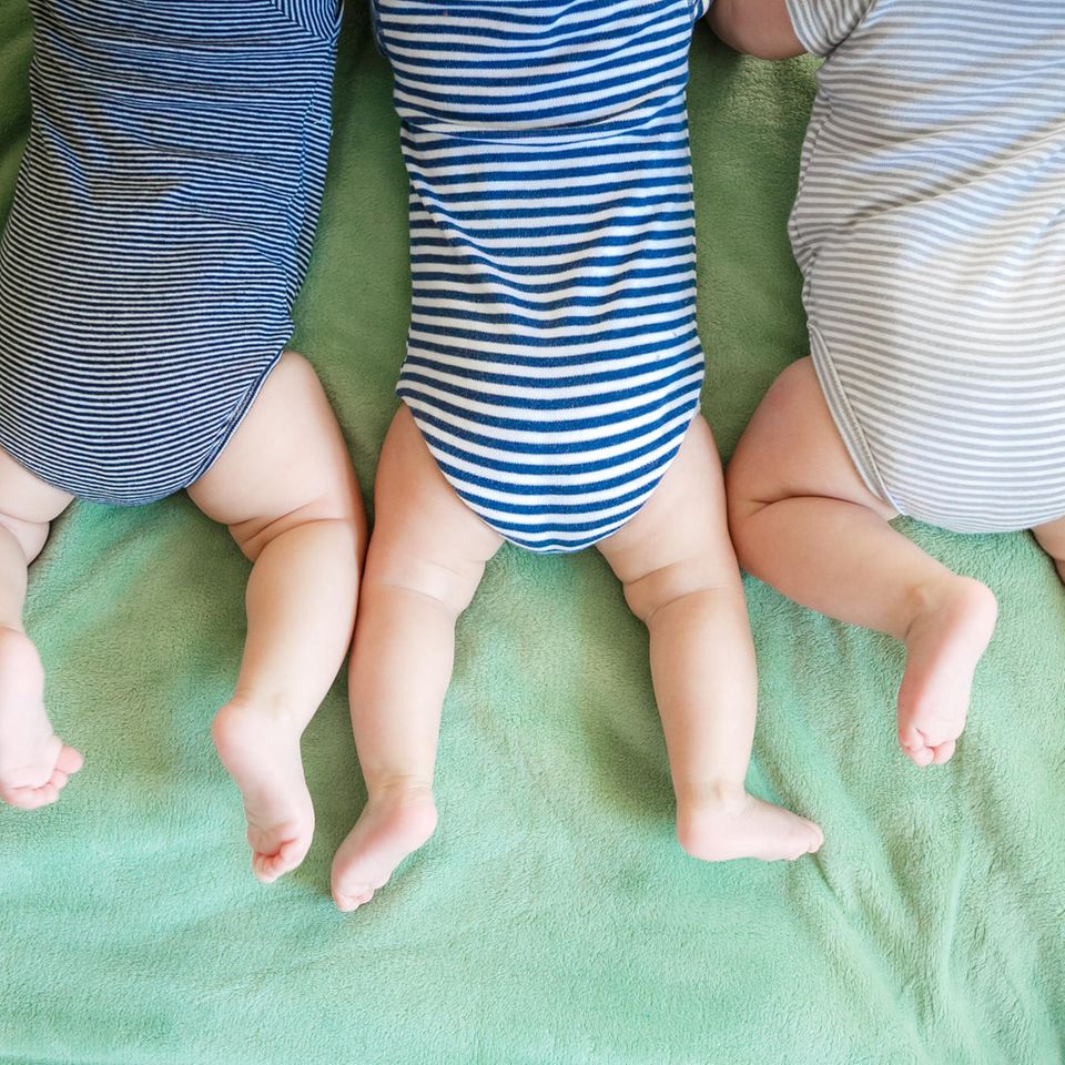 Drei Babys liegen auf dem Bauch
