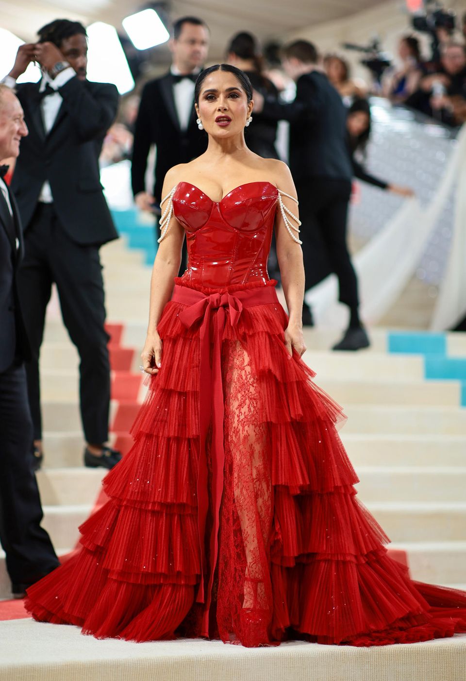 Latex trifft auf Volants: Schauspielerin Salma Hayek weiß in sexy Vokuhila-Robe von Gucci ihre Kurven in Szene zu setzen. Spannendes Detail, das an Chanel erinnert: Die drapierten Perlenbänder an ihren Oberarmen. 