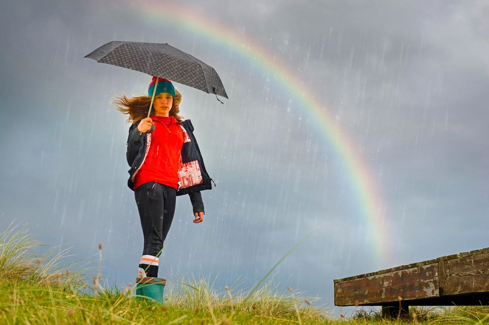 Horoskop: Eine Frau mit Schirm und Regenbogen