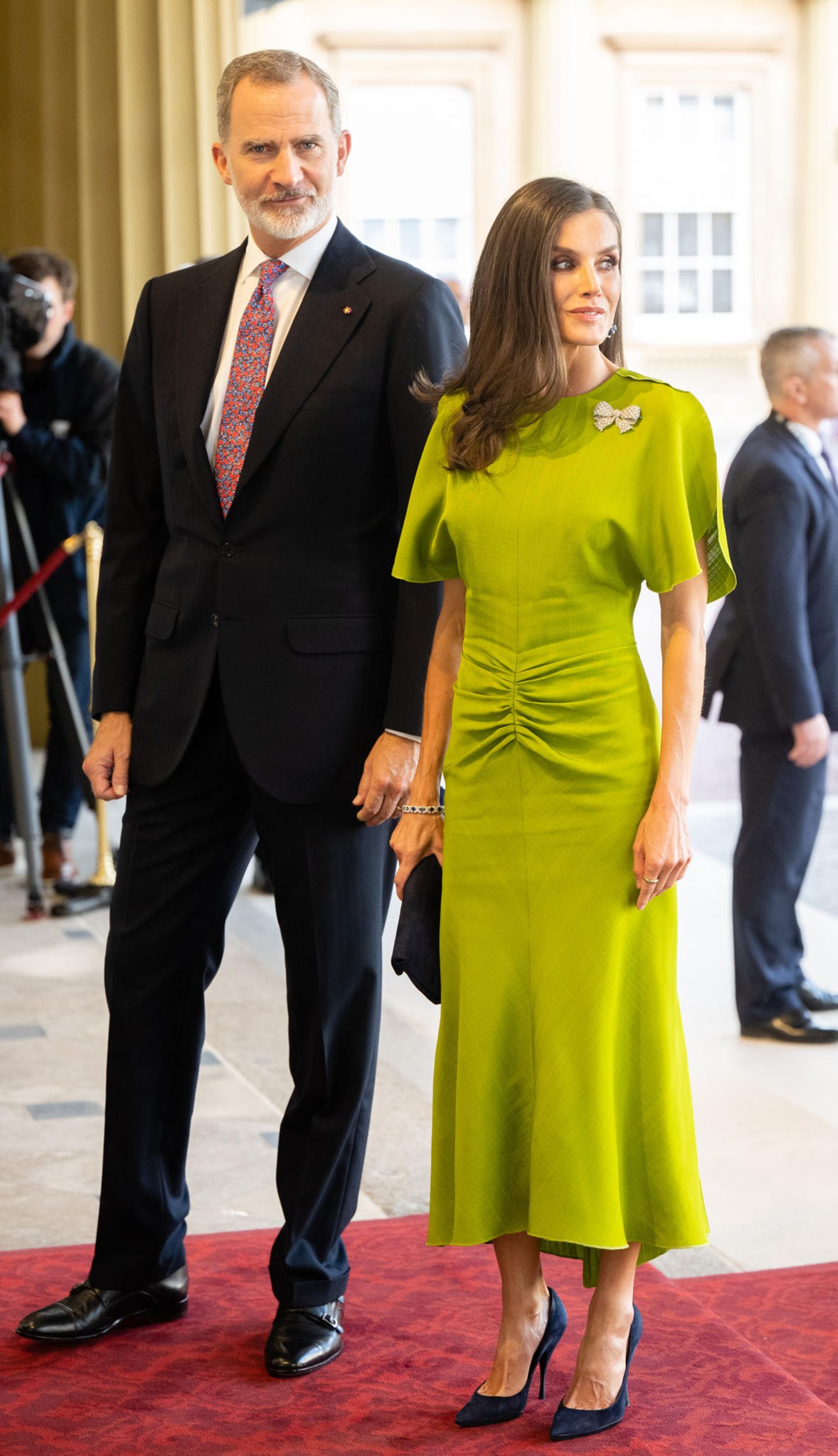 Beim Empfangsdinner im Buckingham Palast begeistert Königin Letizia in einer lindgrünen Kreation der britischen Designerin Victoria Beckham inklusive funkelnder Brosche im Schleifen-Design. Eine Clutch von Nina Ricci und Pumps von Magrit – beides in Dunkelblau – harmonieren perfekt zu ihrem eleganten Look.  