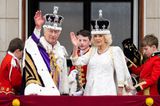 God save the King! Auf dem Balkon des Buckinghampalastes winken der neu gekrönte König und seine Königsgemahlin dem Volk zu. Für dieses Ereignis hat sich Charles noch einmal umgezogen, trägt zum weißen Hemd mit Distelstickereien eine Jacke in Purpur – noch heute noch der teuerste Farbstoff und ein Symbol des Adels. Königin Camilla bleibt in ihrem Krönungsoutfit und strahlt im A-Linien-Kleid mit 3/4-Ärmeln und goldenen Details von Bruce Oldfield.
