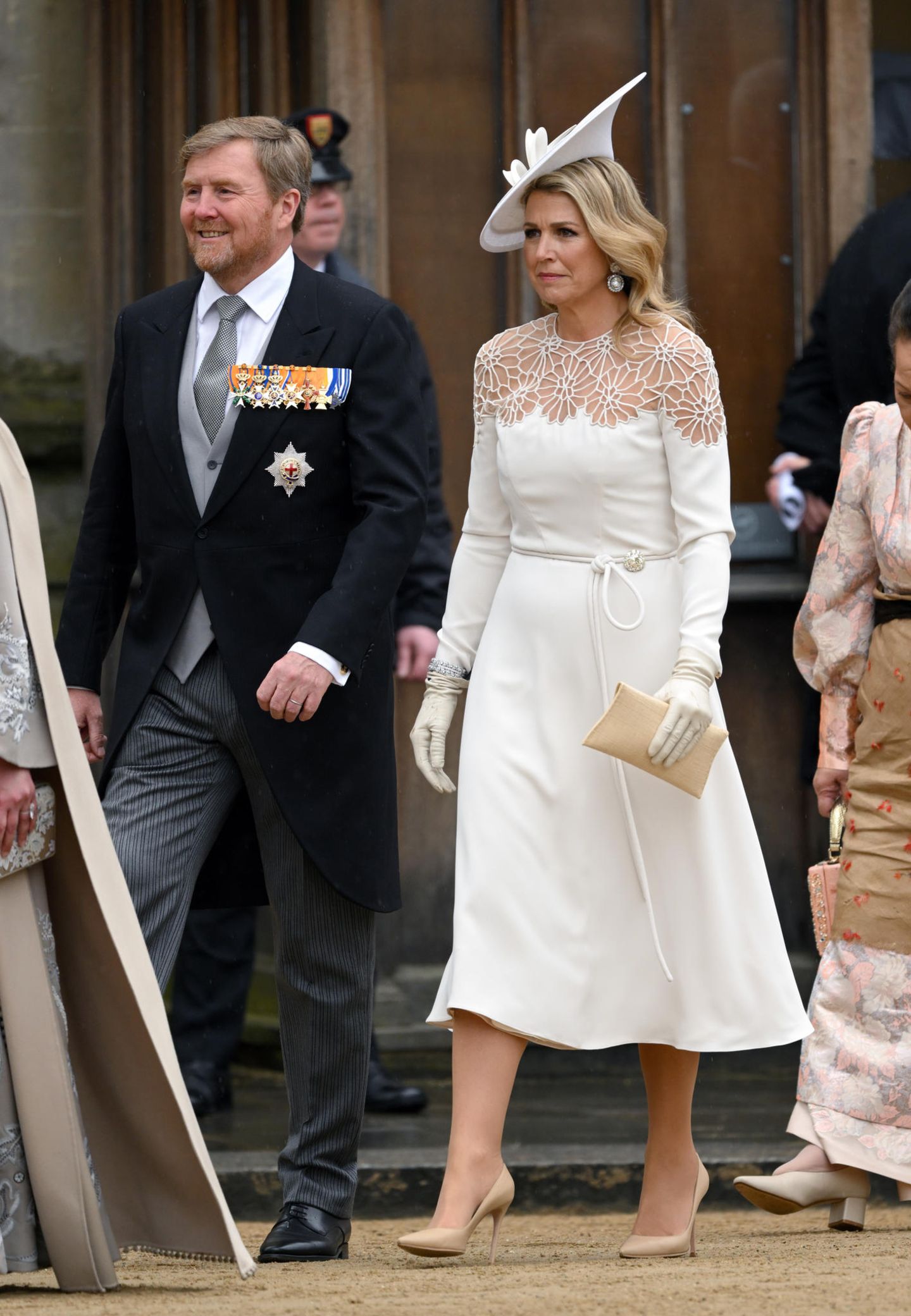 Ein Traum in Weiß! Ähnlich wie weibliche Mitglieder des britischen Königshauses setzt Königin Màxima auf eine helle Robe – hier von Jantaminiau. Dazu kombiniert sie cremefarbene Pumps und Tasche sowie einen extravaganten Hut von Philip Treacy. 