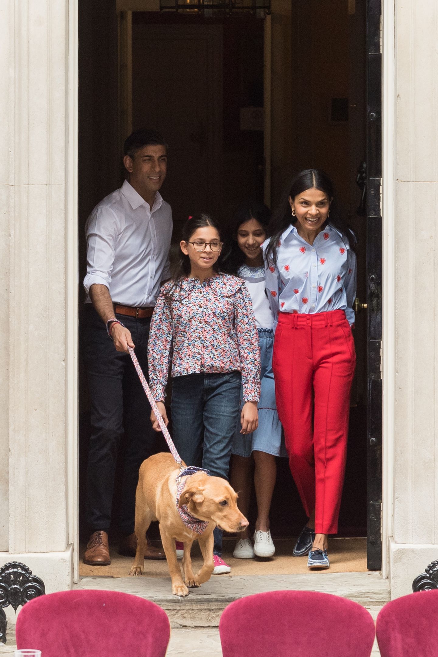 Elegant, britisch, chic: Akshata Murty, die Ehefrau von Englands Prime Minister Rishi Sunak zeigt sich an der Seite ihres Mannes und der beiden gemeinsamen Töchter beim großen Krönungsmittagessen in der Downing Street. Für diesen Anlass wählt sie eine Herzchen-Bluse von Boden sowie eine passende rote Stoffhose und Segelschuhe in Blau. 