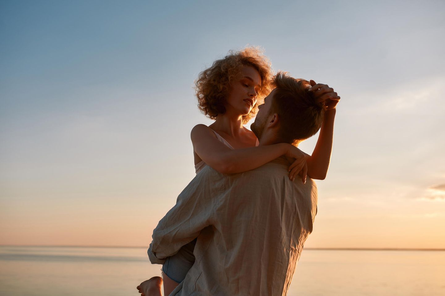 Allosexualität: Verliebtes Paar umarmt sich innig am Strand vor dem Sonnenuntergang