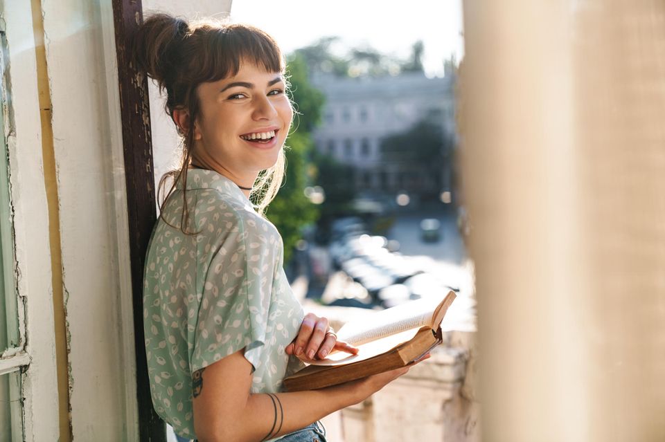Glückliche Frau auf dem Balkon: Diese 4 Eigenschaften teilen erfolgreiche Menschen