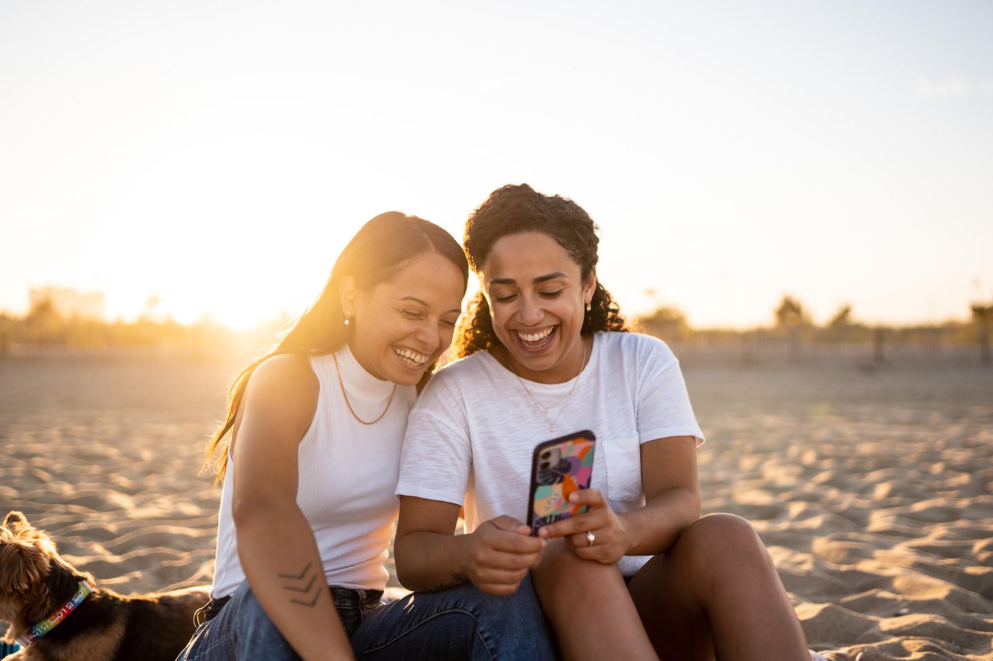 Zwei Frauen sprechen und schauen auf ein Handy: 4 Tipps, mit denen du es deinem Gegenüber leichter machst, sich zu öffnen
