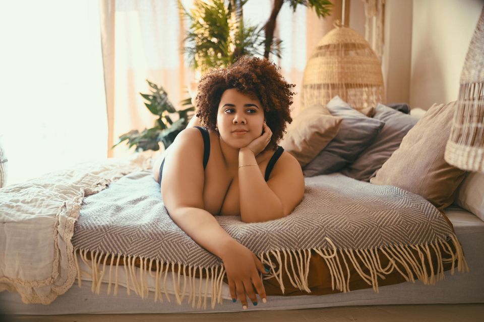 Eine Frau liegt nachdenklich auf ihrem Bett