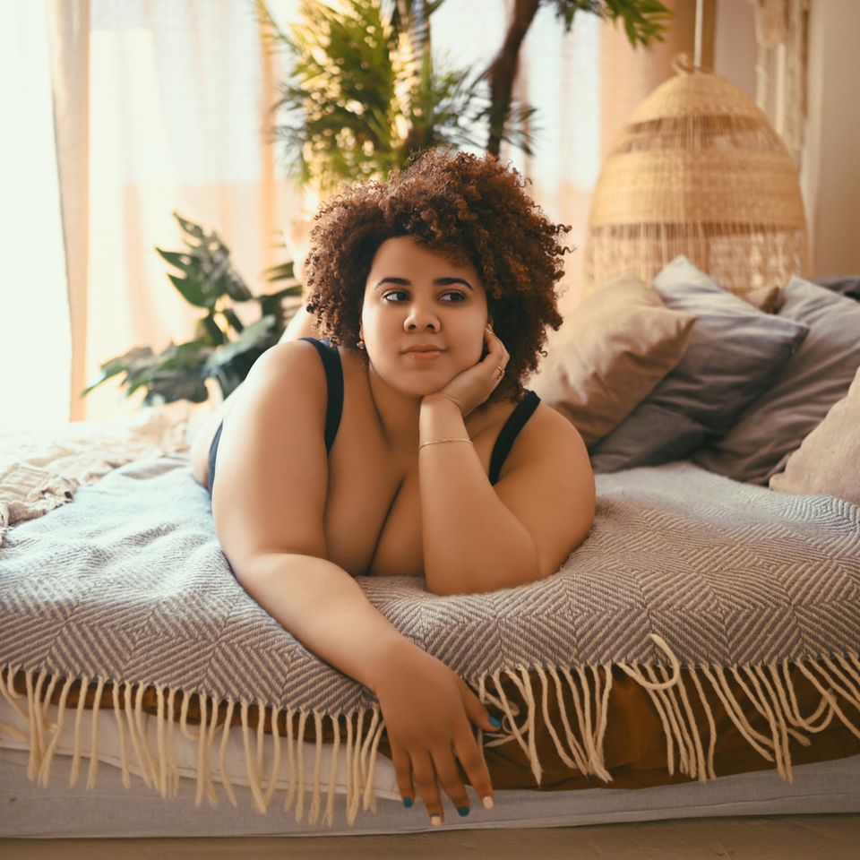 Eine Frau liegt nachdenklich auf ihrem Bett