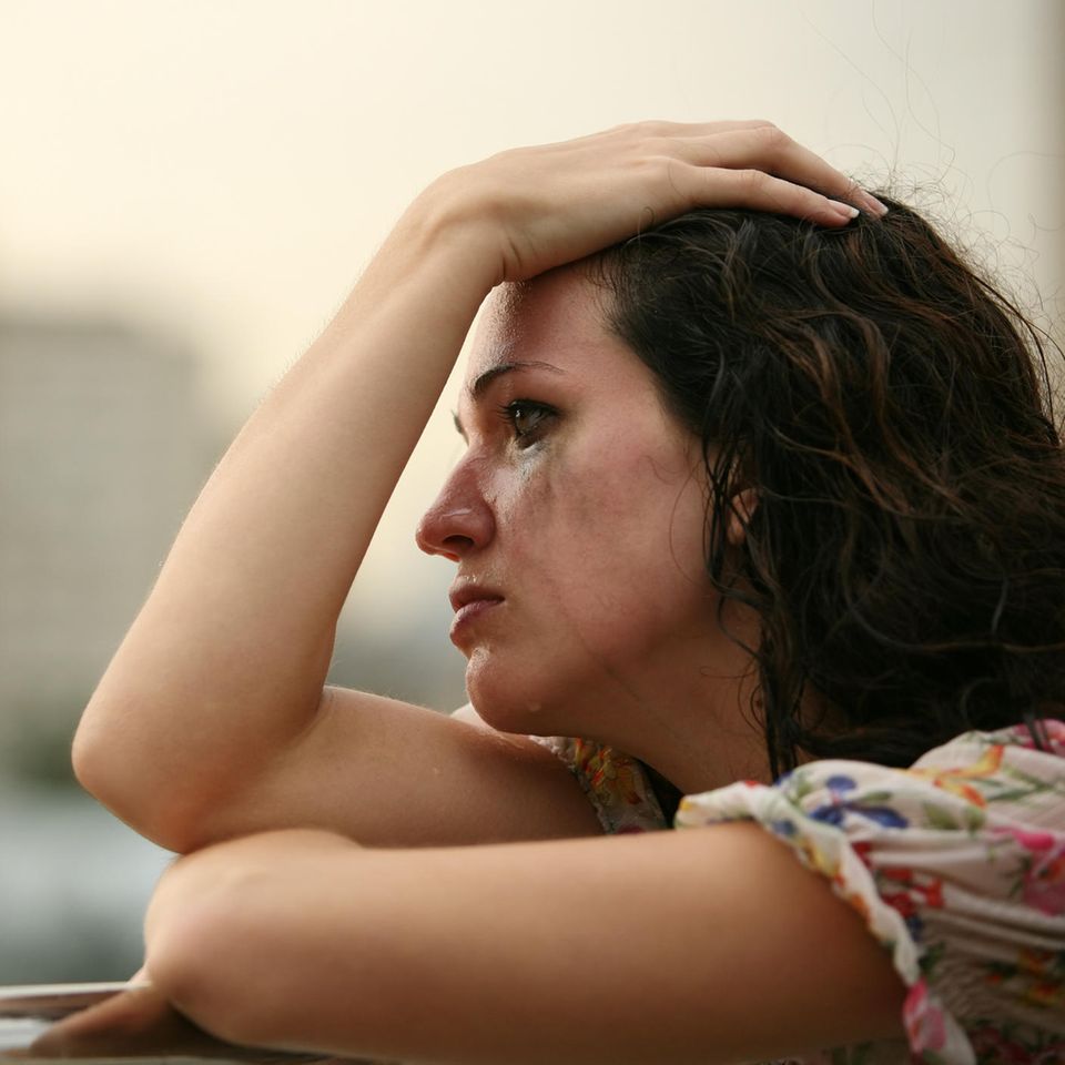 Eine Frau steht weinend auf ihrem Balkon