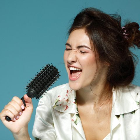 Eine Frau singt und nutzt ihre Haarbürste als Mikrofon