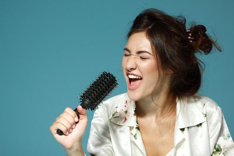 Eine Frau singt und nutzt ihre Haarbürste als Mikrofon