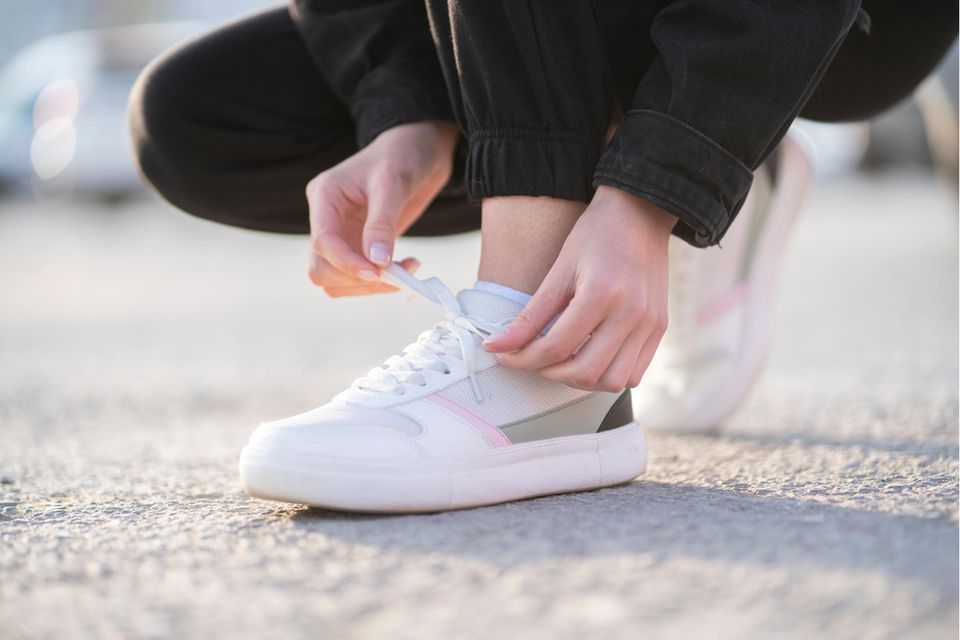 Schuhe stinken: Nahaufnahme, wie sich eine Frau die Sneaker zubindet