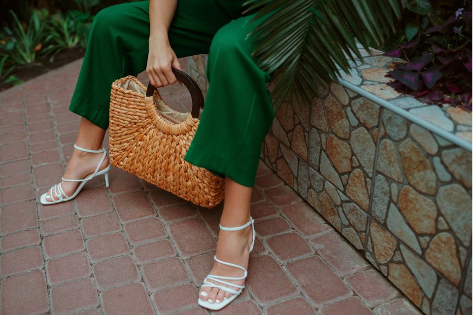Deals des Tages: Frau trägt weiße Sandalen zu grüner Hose