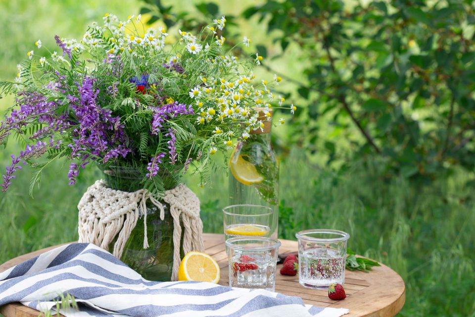 Gläser dekorieren: Tisch im Garten mit Blumenstrauß und Trinkgläsern
