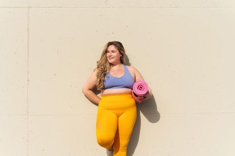 Sportliche Frau steht an einer Mauer: Sind 5 Minuten Sport pro Tag genug, um fit zu bleiben?