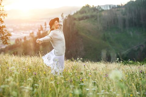 Horoskop: Eine fröhliche Frau auf einem Hügel