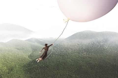 Psychologie: Eine Frau fliegt an einem Ballon über Berge