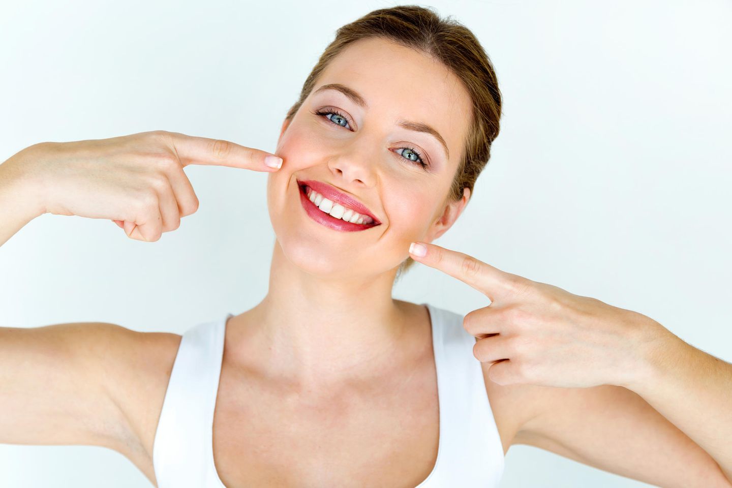 Ölziehen: Eine Frau zeigt auf ihr strahlend-weißes Lächeln