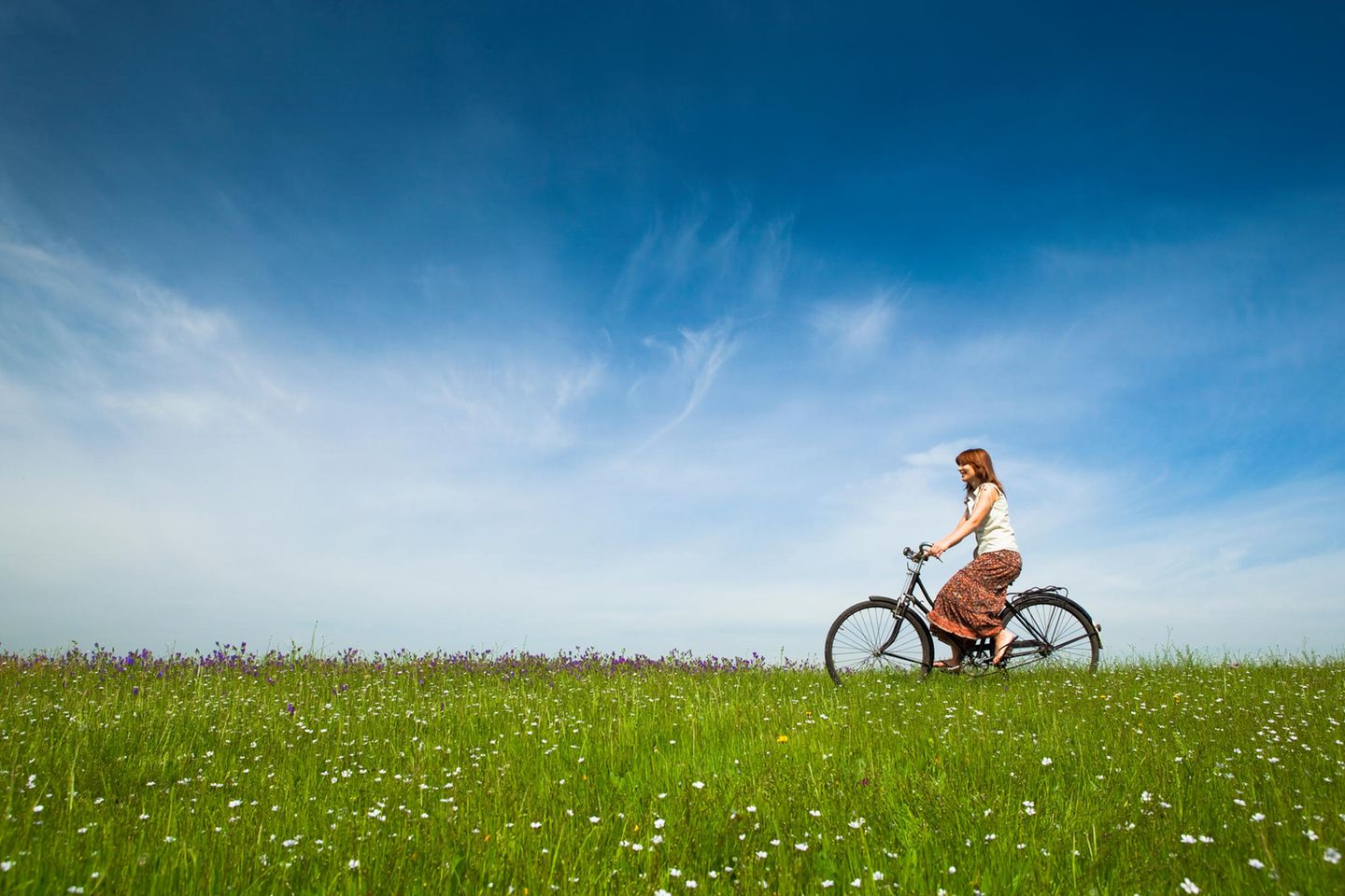 Eine Frau auf einem Fahrrad fährt auf einer Wiese