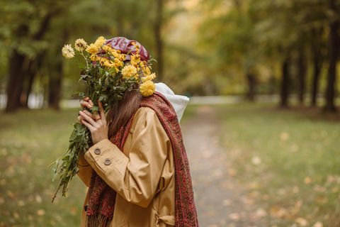 Horoskop: Eine Frau versteckt sich hinter einem Blumenstrauß