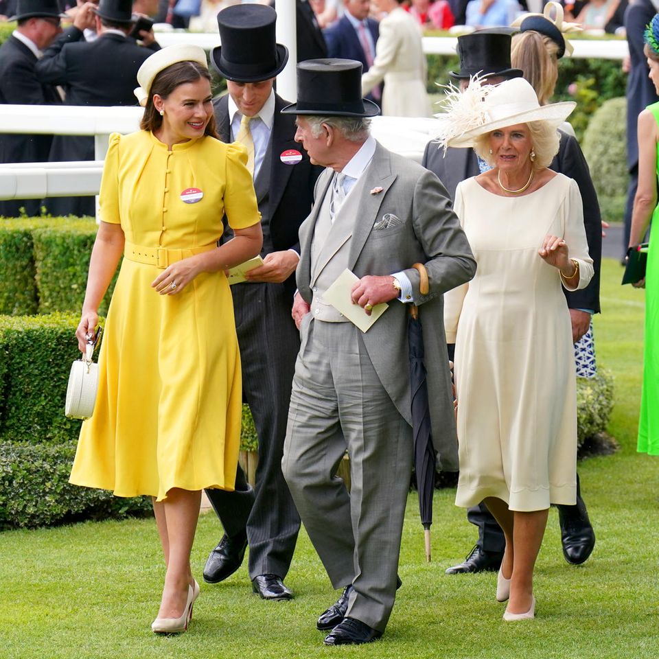 König Charles ist bei dem Royal Ascot Pferderennen in Begleitung von Lady Sophie Winkleman. Sie ist die Ehefrau von Lord Frederick Windsor, der Sohn von Prinz Michael von Kent, der wiederum ein Cousin von Queen Elizabeth ist. Sie ist eine berühmte Schauspielerin, kommt aber auch familiären Aufgaben nach. Sie setzt i Ascot im Gegensatz zu Camilla auf eine kräftige Farbe und strahlt in einem schönen Sonnengelb. 