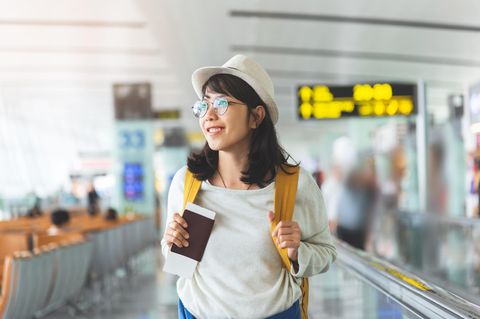 Glückliche Frau am Flughafen: 5 Fehler, die ich beim Reisen nicht mehr mache