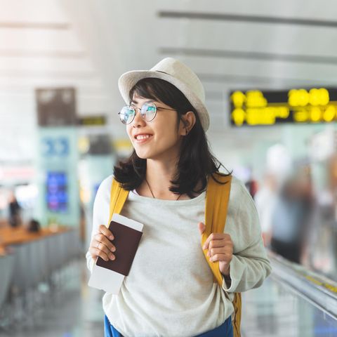 Glückliche Frau am Flughafen: 5 Fehler, die ich beim Reisen nicht mehr mache