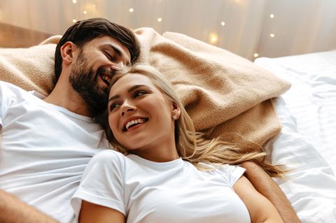 Analsex: Frau und Mann liegen sich in den Armen im Bett