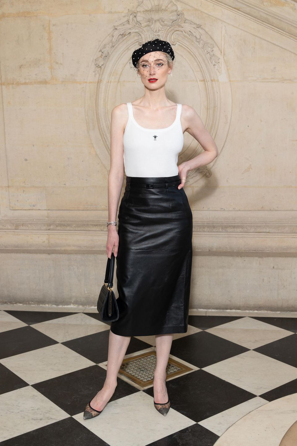 Klassischer kann ein Look kaum aussehen! Elizabeth Debicki erschient zur Dior-Show mit Barret, weißem Top und Lederrock. Spitze Pumps und eine Vintage-Tasche runden den Look ab. 