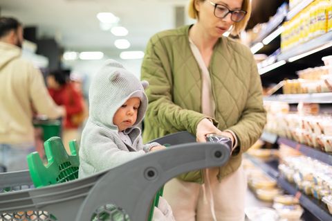 Kind im Einkaufswagen im Supermarkt mit Mutter
