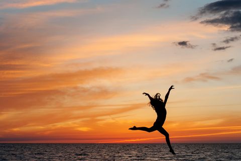 Wochenhoroskop ab 10.7.: Eine springende Frau am Strand
