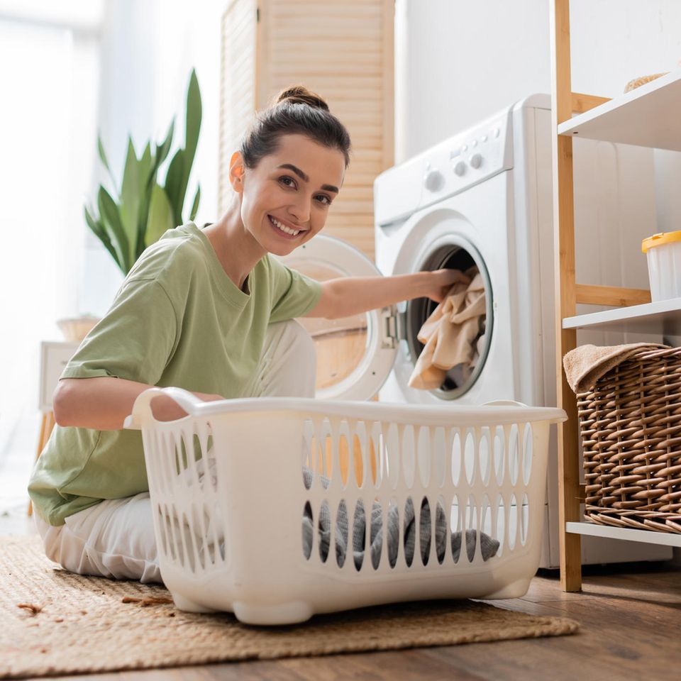 Wäsche waschen: Frau befüllt Waschmaschine