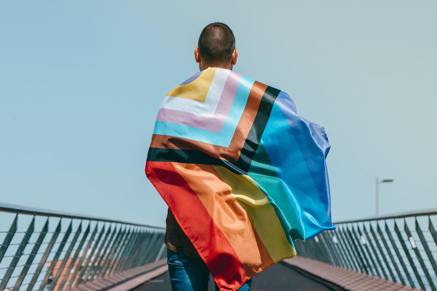 Intersexualität: Person mit LGBTQIA-Flagge steht mit dem Rücken zur Kamera