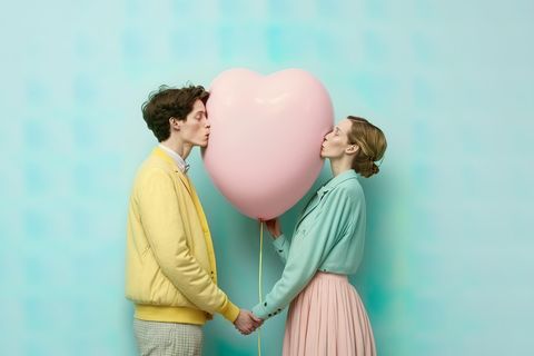 Zwei Menschen küssen denselben Herzballon
