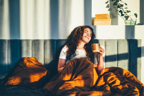 glückliche Frau im Bett mit Tasse