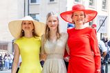 Dieses royale Style-Trio sorgt in Brüssel für Begeisterung! Königin Mathilde feiert mit ihrer Familie und allen Belgiern am 21. Juli den Nationalfeiertag, und nicht nur ihr feuerrotes Outfit von Natan Couture erfreut ihre Fans, auch ihre Töchter verzaubern mit ihren Looks: Prinzessin Elisabeth (l.) trägt einen eleganten Sommerlook in Gelb, ebenfalls von Natan Couture, und ihre jüngere Schwester Prinzessin Eleonore glänzt in der Mitte in einem hellgoldenem Volant-Lamé-Dress von Maje Paris.