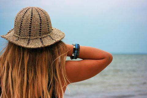 Frau am Strand zeigt Armbänder