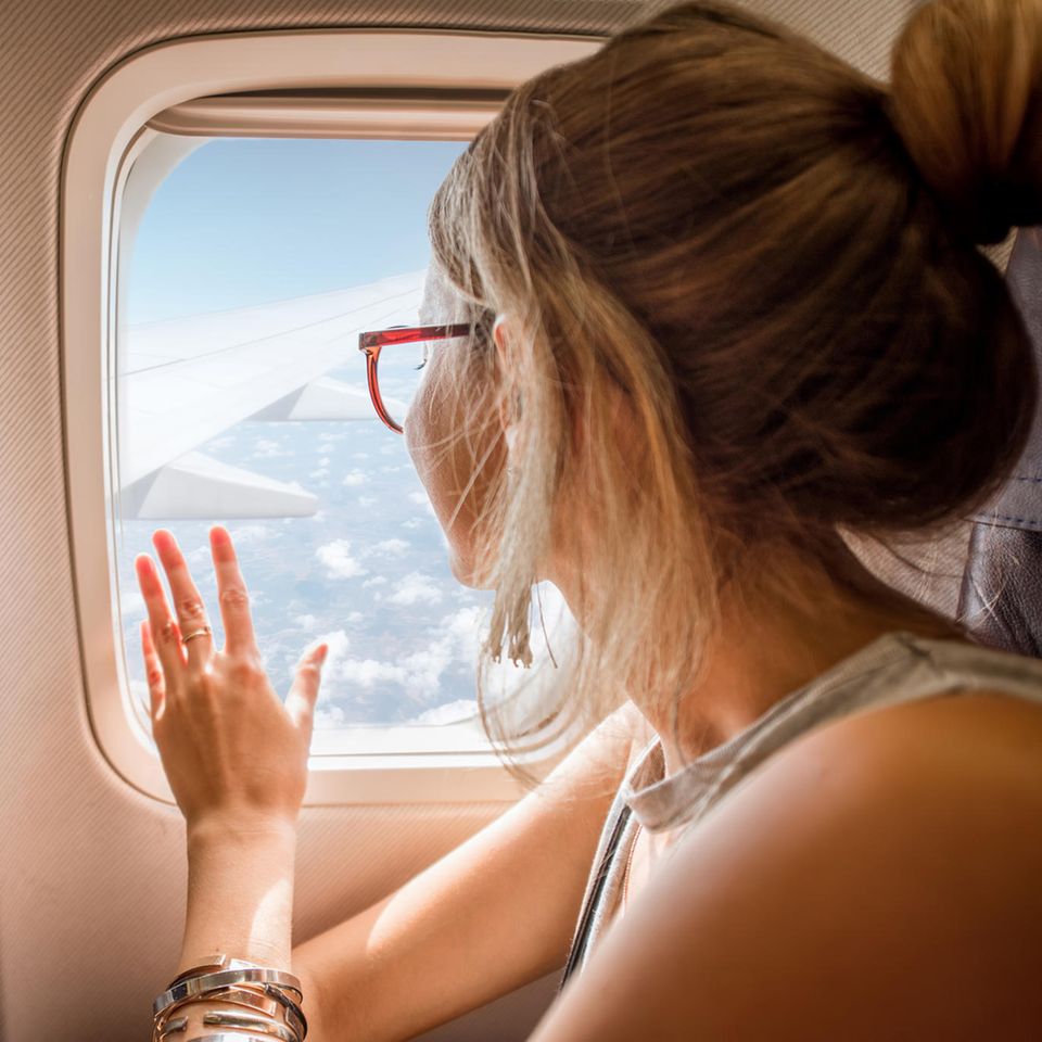 Frau blickt aus dem Flugzeugfenster